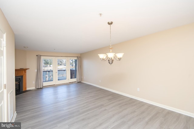 unfurnished living room with a chandelier, a fireplace with flush hearth, light wood-style flooring, and baseboards