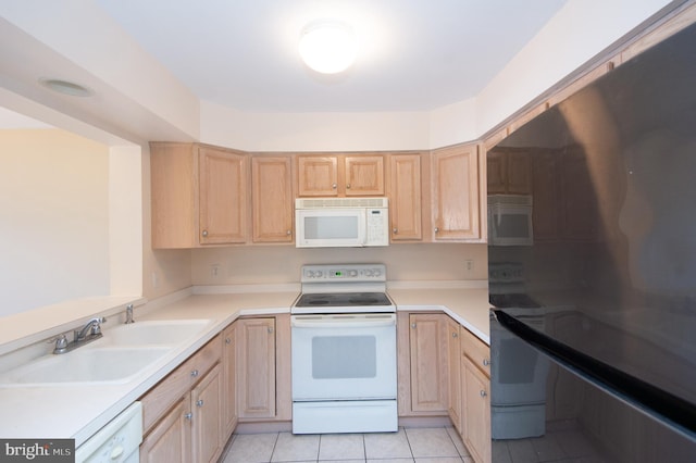 kitchen featuring light countertops, white appliances, light brown cabinets, and a sink