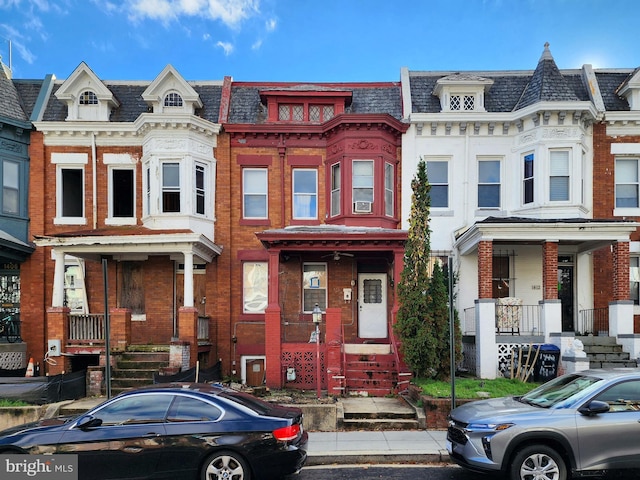 view of front facade with mansard roof, a high end roof, and brick siding