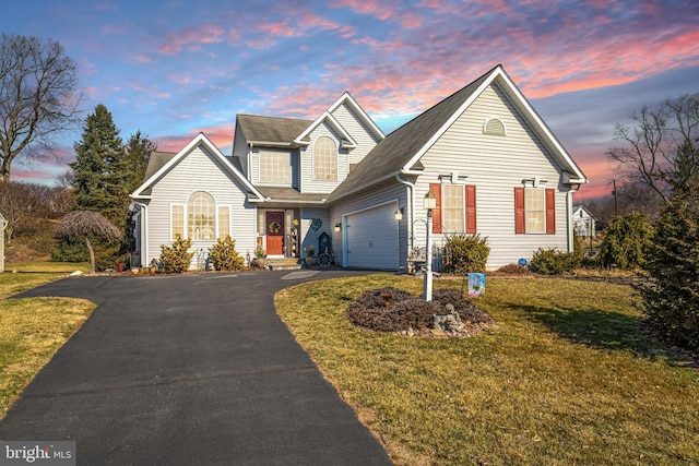 traditional-style home with aphalt driveway, a front yard, and an attached garage