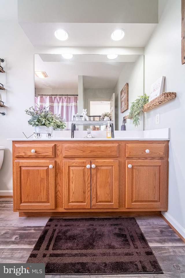 bathroom with toilet, wood finished floors, and vanity