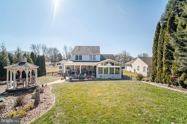 rear view of house featuring fence, a sunroom, a gazebo, a yard, and a patio area