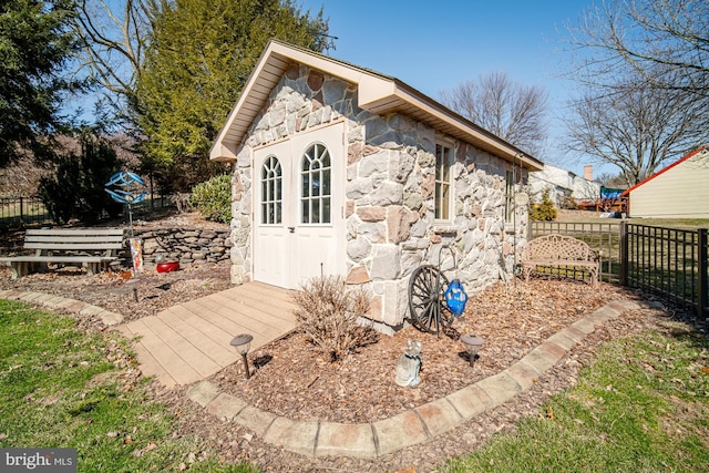 view of outdoor structure featuring fence and an outbuilding