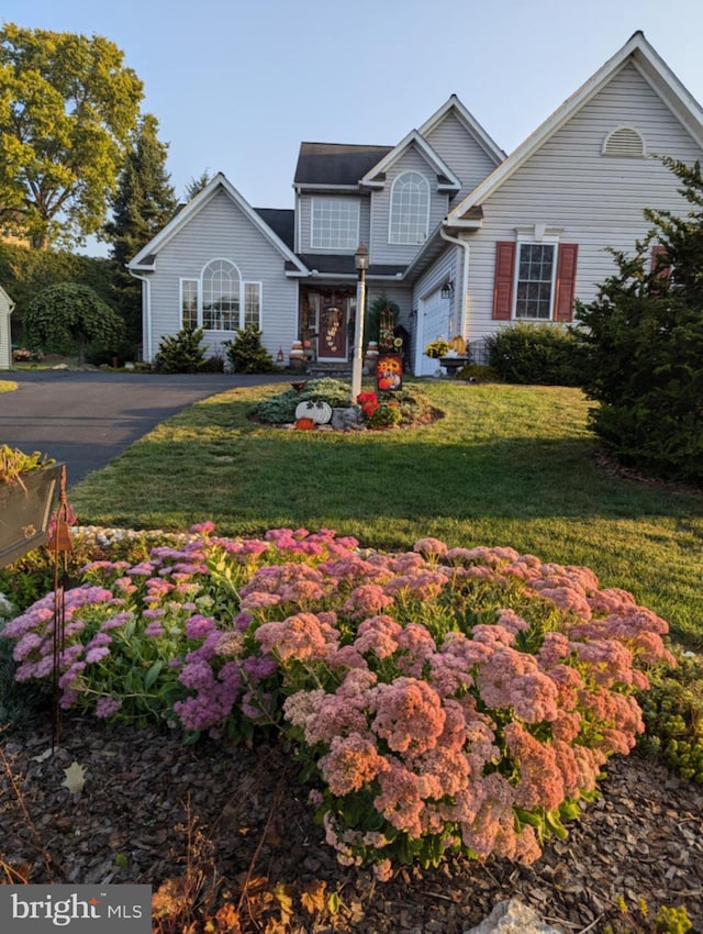 traditional-style house with aphalt driveway and a front yard