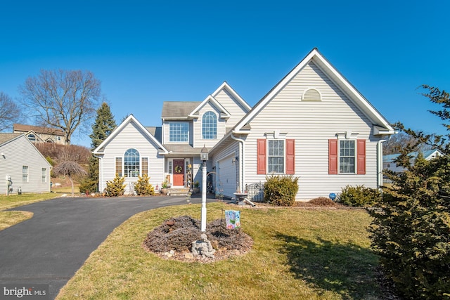 traditional-style home featuring a garage, driveway, and a front lawn