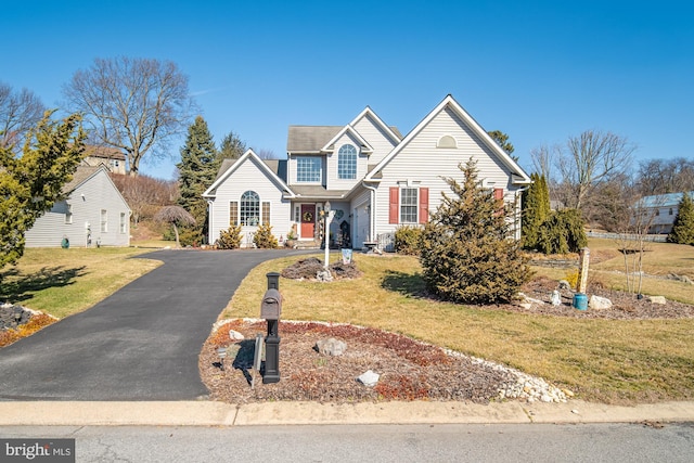 traditional-style house featuring aphalt driveway and a front yard