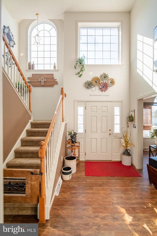 foyer with plenty of natural light, wood finished floors, and a towering ceiling