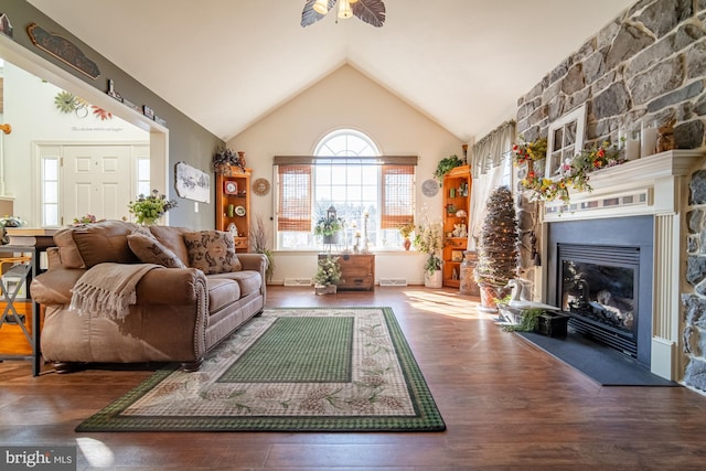 living area featuring vaulted ceiling, a glass covered fireplace, wood finished floors, and a ceiling fan