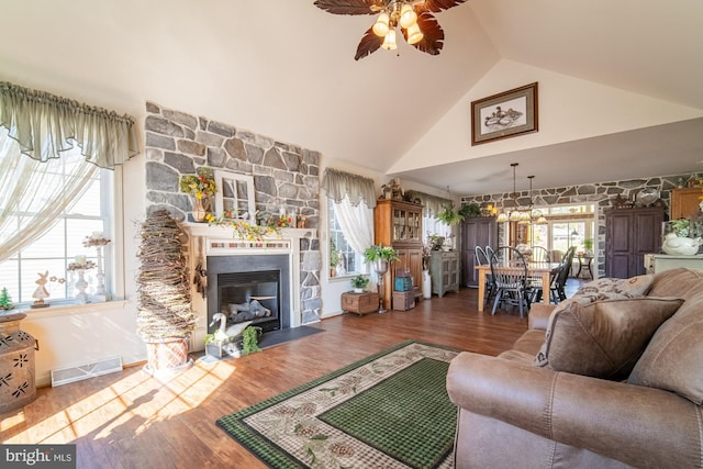 living area featuring a fireplace, visible vents, a ceiling fan, wood finished floors, and high vaulted ceiling