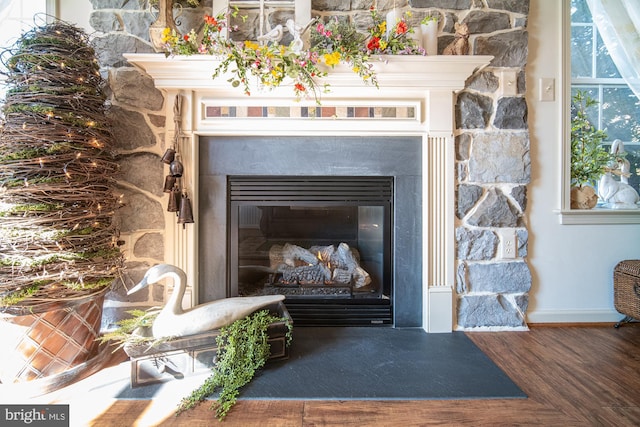 room details featuring wood finished floors, a glass covered fireplace, and baseboards