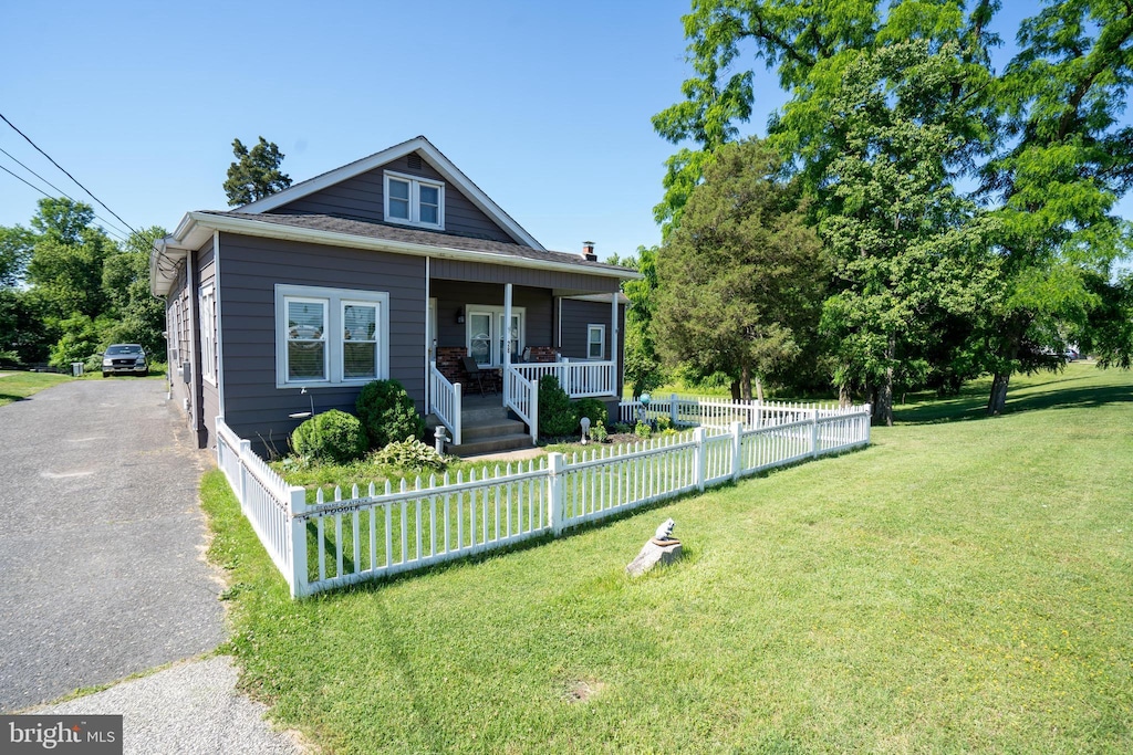 bungalow-style home featuring a fenced front yard, covered porch, and a front lawn