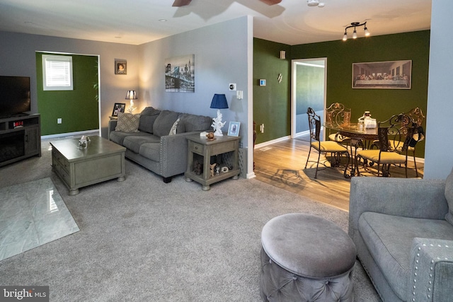 living area featuring ceiling fan, baseboards, and wood finished floors