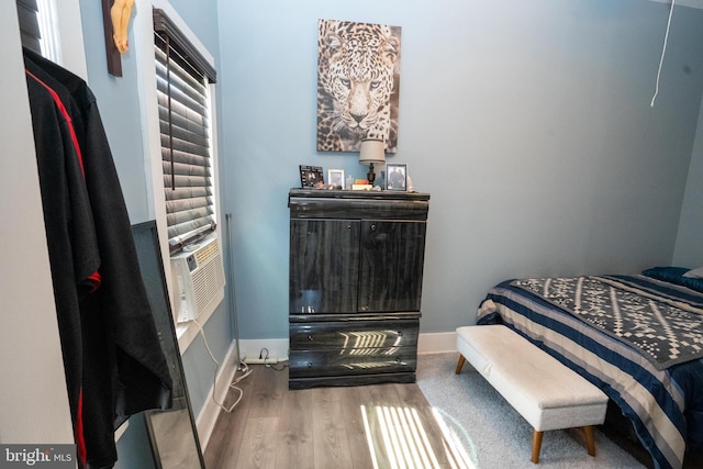 bedroom featuring cooling unit, wood finished floors, and baseboards