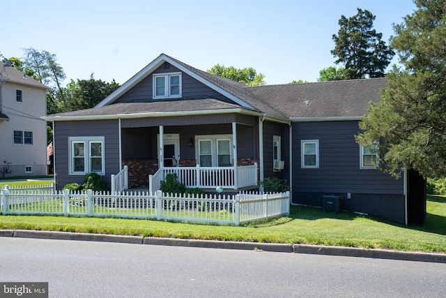 view of front of home featuring a fenced front yard, central air condition unit, covered porch, roof with shingles, and a front yard