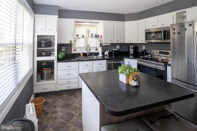 kitchen featuring stainless steel appliances, dark countertops, white cabinets, and a sink