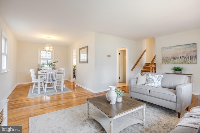 living room featuring light wood-type flooring, stairs, and baseboards