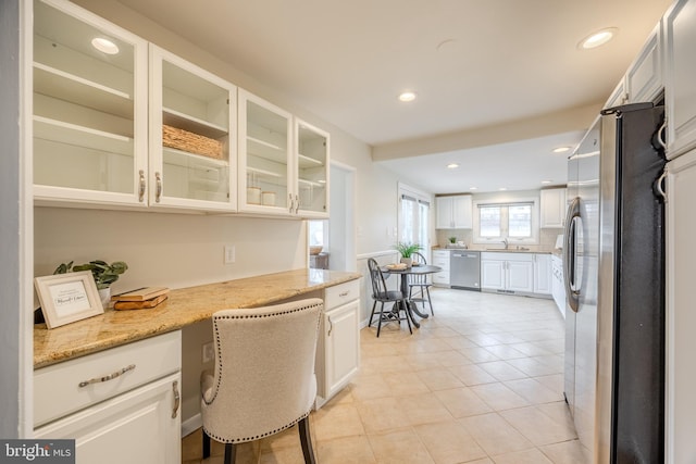 kitchen with light tile patterned floors, recessed lighting, white cabinetry, appliances with stainless steel finishes, and built in desk