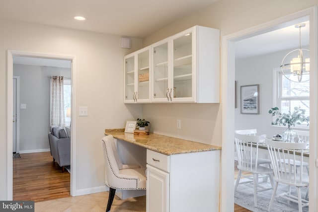 kitchen with light stone counters, glass insert cabinets, and white cabinets