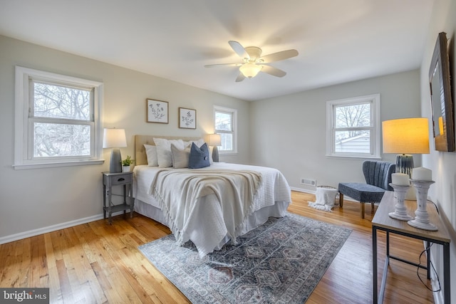 bedroom with baseboards, visible vents, hardwood / wood-style floors, and multiple windows