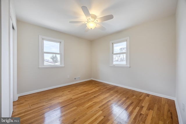 spare room featuring light wood-style floors, visible vents, ceiling fan, and baseboards