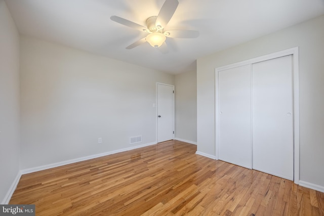 unfurnished bedroom featuring light wood finished floors, baseboards, visible vents, ceiling fan, and a closet