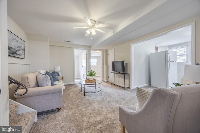 carpeted living room featuring visible vents, a ceiling fan, and baseboards