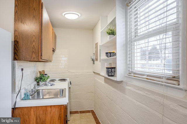 kitchen with brown cabinetry, light countertops, a sink, and decorative backsplash