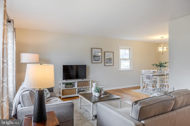 living area with an inviting chandelier, visible vents, baseboards, and wood finished floors