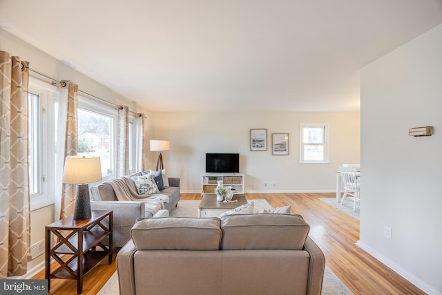 living room with a healthy amount of sunlight, light wood-style floors, and baseboards