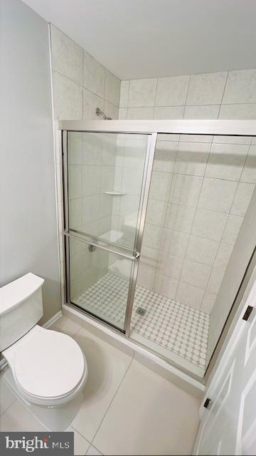 bathroom with tile patterned flooring, a shower stall, and toilet