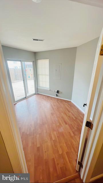 unfurnished room with baseboards, visible vents, and wood finished floors