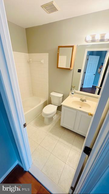 bathroom with toilet, vanity, baseboards, visible vents, and tile patterned floors