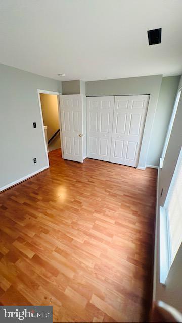 unfurnished bedroom with a closet, baseboards, and light wood finished floors