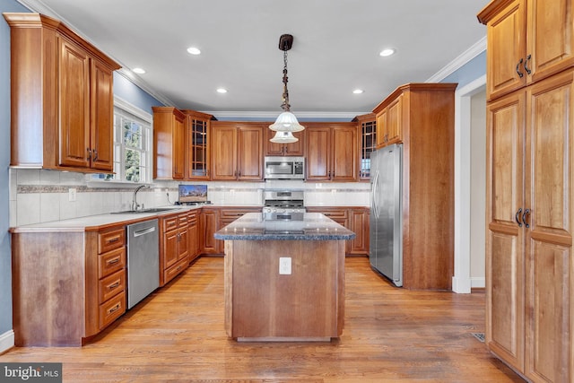 kitchen featuring light wood-style flooring, a sink, a center island, stainless steel appliances, and crown molding