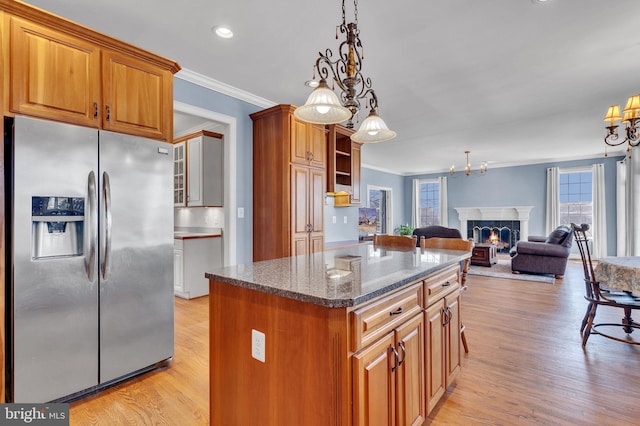 kitchen featuring brown cabinets, ornamental molding, stainless steel refrigerator with ice dispenser, open floor plan, and a fireplace