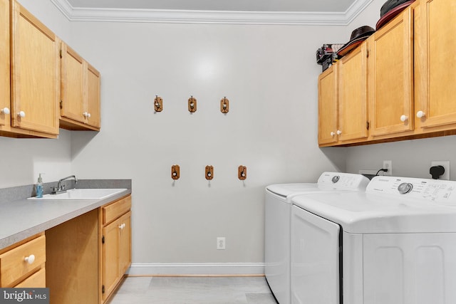 laundry area with a sink, cabinet space, washing machine and dryer, and crown molding