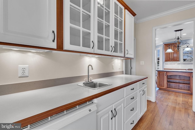 kitchen featuring crown molding, white cabinets, white dishwasher, and a sink