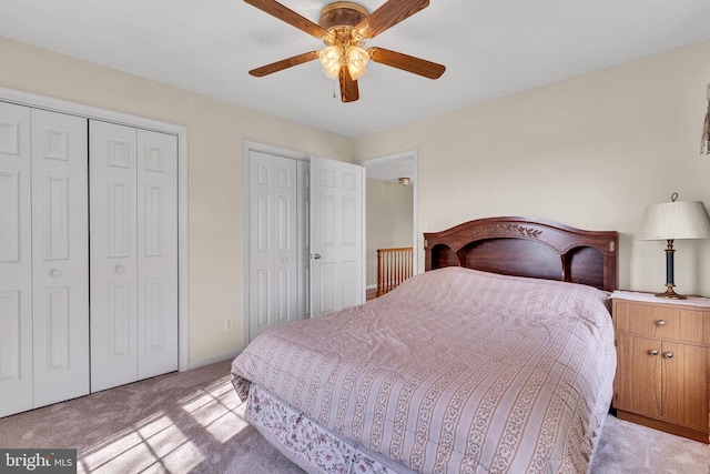 bedroom with baseboards, light carpet, two closets, and ceiling fan