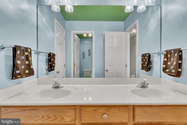 bathroom with double vanity, toilet, and a sink