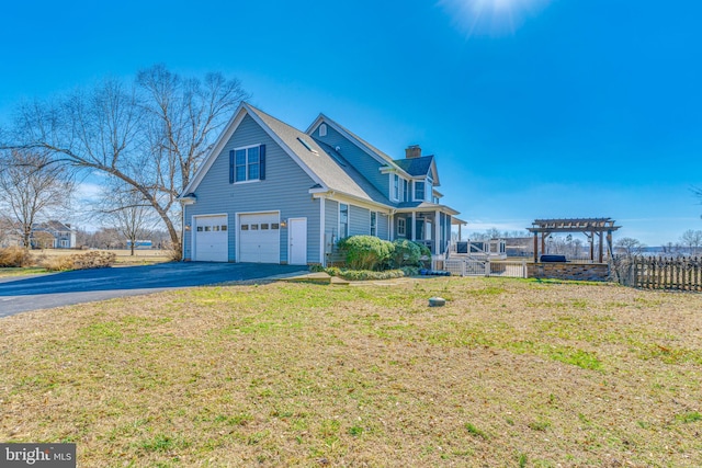 view of home's exterior with driveway, a yard, an attached garage, a pergola, and a chimney