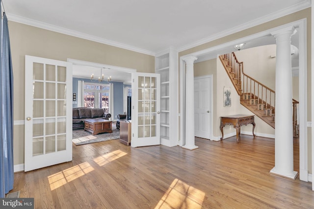 interior space featuring stairs, french doors, wood finished floors, and ornate columns