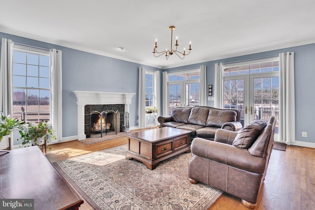 living area with a high end fireplace, ornamental molding, a wealth of natural light, french doors, and wood finished floors