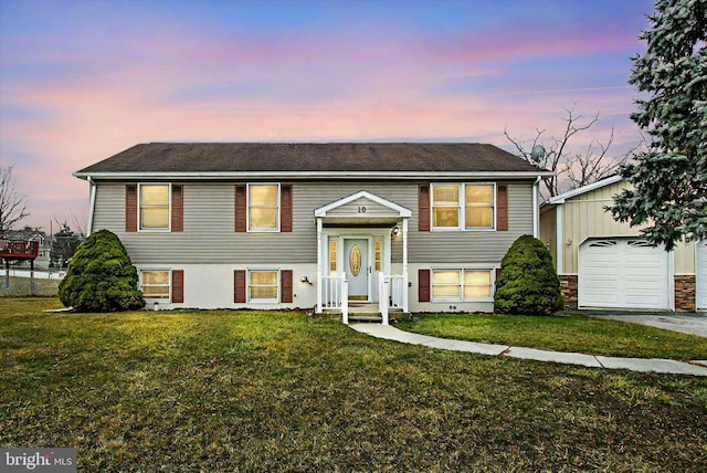 split foyer home with a detached garage, a front lawn, and an outbuilding