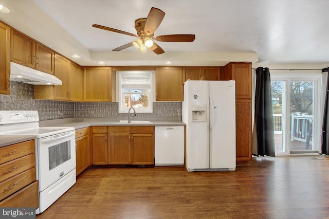 kitchen featuring white appliances, a sink, under cabinet range hood, and wood finished floors