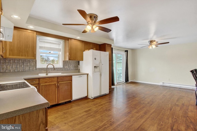 kitchen featuring white appliances, baseboard heating, wood finished floors, and tasteful backsplash