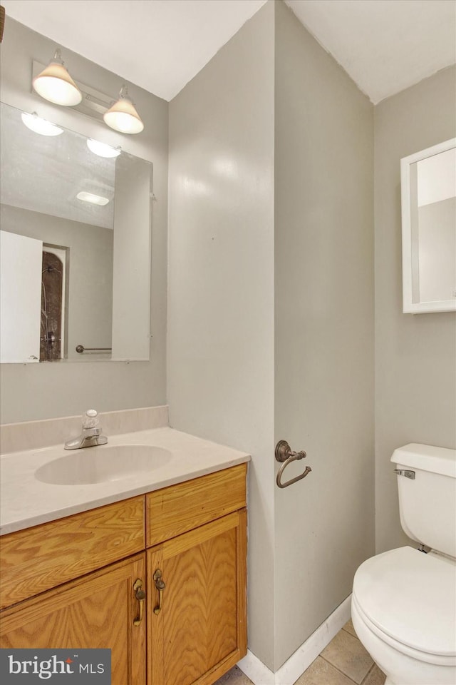 bathroom with toilet, tile patterned flooring, baseboards, and vanity