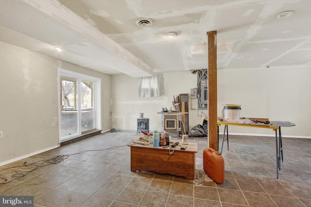 interior space featuring a wood stove, baseboards, and visible vents