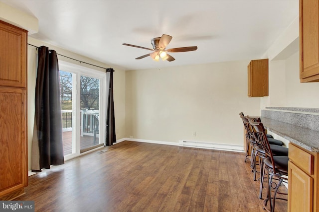 unfurnished dining area with a ceiling fan, a baseboard radiator, dark wood finished floors, and baseboards