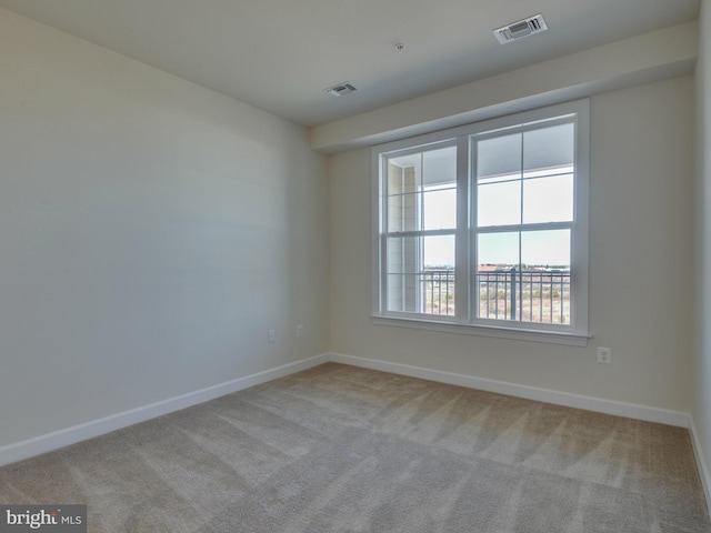 spare room with carpet flooring, visible vents, and baseboards