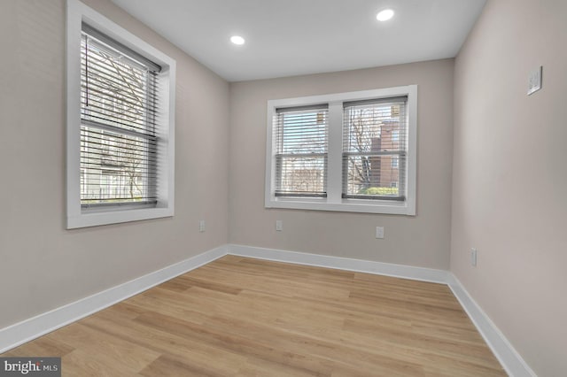 empty room with light wood-style floors, plenty of natural light, and baseboards